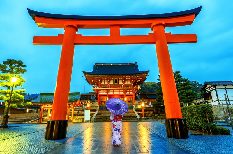 Wearing kimonos at Fushimi Inari Shrine in Kyoto is a memorable experience on youth trips to Japan, blending cultural tradition with the stunning backdrop of endless torii gates.